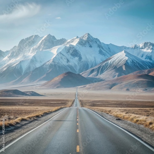 A straight road stretches into the distance, leading towards a range of snow-capped mountains.