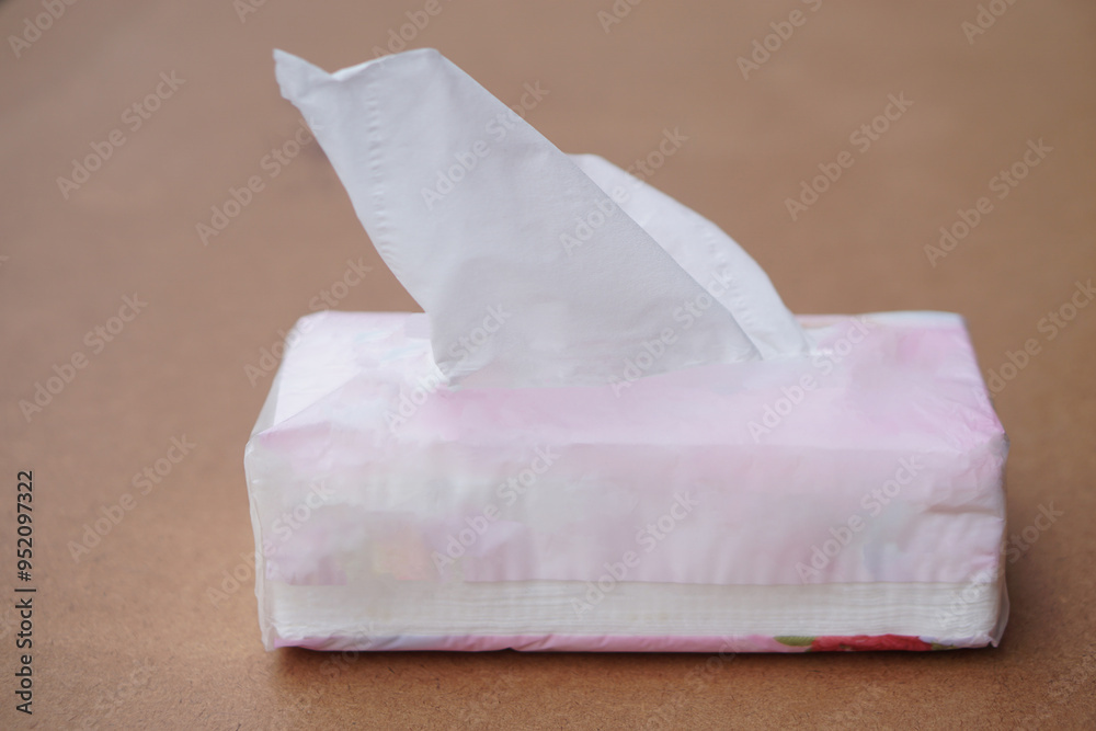 Sheet tissue paper package, on brown background. Concept, item for cleaning, wiping or absorbing dirt from face, skin or other purposes for hygienic and sanitary daily life. Sheet tissue paper package, on brown background. Concept, item for cleaning, wiping or absorbing dirt from face, skin or other purposes for hygienic and sanitary daily life.