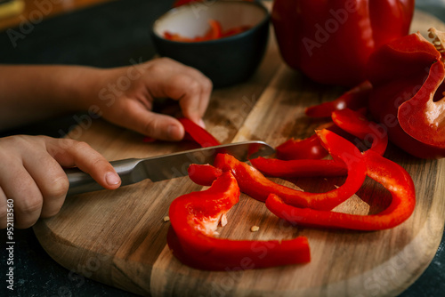 Girl cutting red pepper on a cutting board