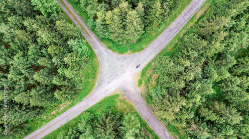 Aerial drone view of dirt road junction in green forest, top view of nature landscape and roads intersection from above
