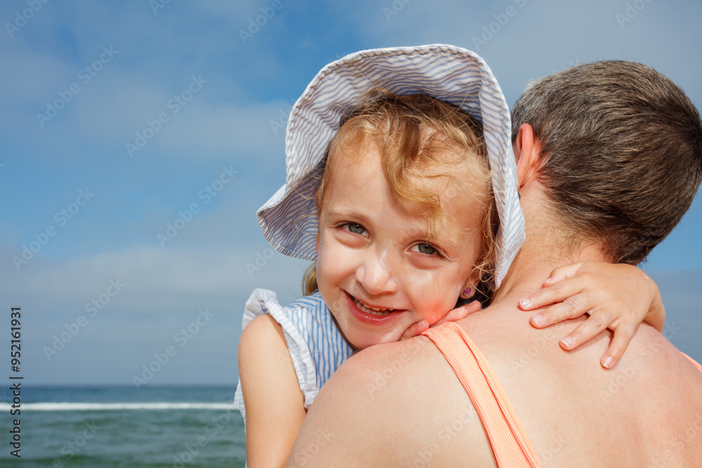 A happy child girl hugs her mother at the beach under blue sky A happy child girl hugs her mother at the beach under blue sky