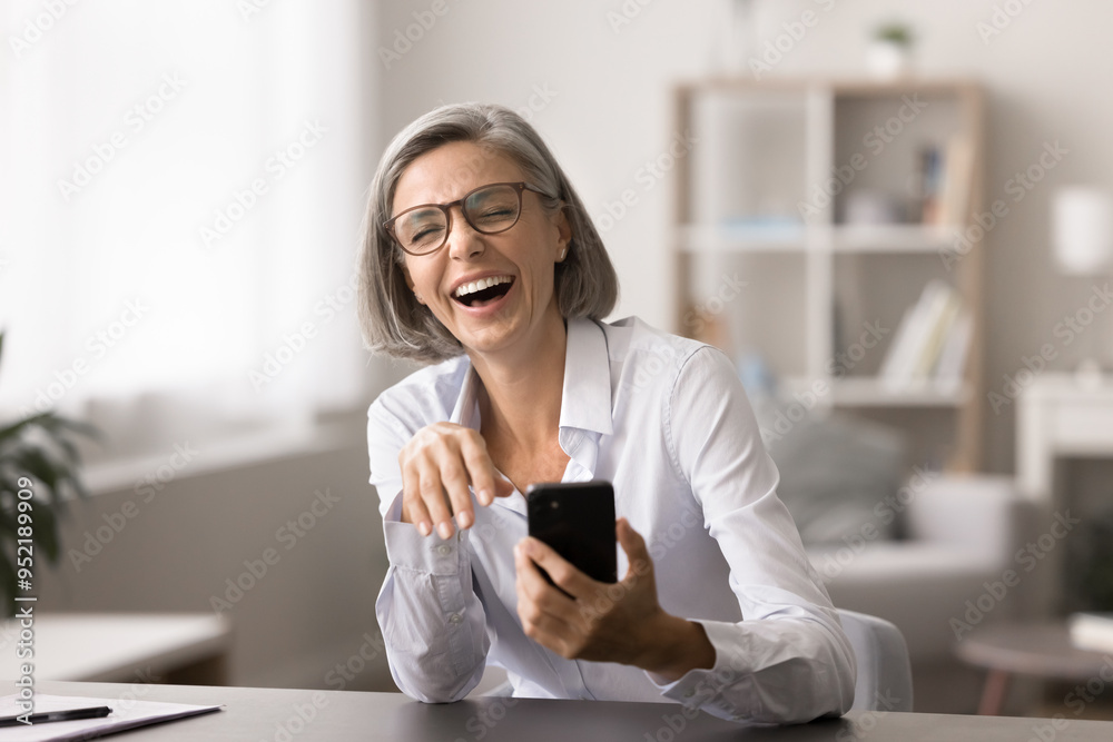 Happy businesswoman laughing, sit at desk with modern smartphone, achieving sales goal, received great news about promotion or bonus, positive client feedback, giggling on funny joke from colleague Happy businesswoman laughing, sit at desk with modern smartphone, achieving sales goal, received great news about promotion or bonus, positive client feedback, giggling on funny joke from colleague