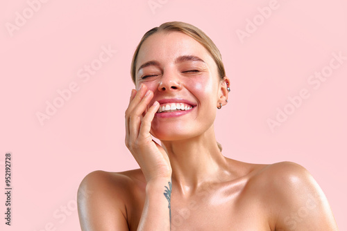 Картината върху платно Beautiful young blonde woman with glowing healthy moist skin laughing and posing with closed eyes on soft pink background