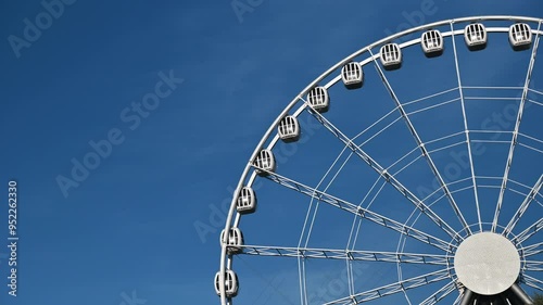 The attraction wheel rotates in the photo of the blue sky. An entertaining carousel on a hot summer day. Amusement park , spinning wheel on a blue sky background. High quality 4k footage