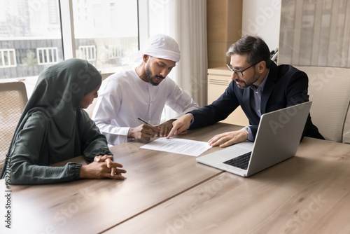 Canvas Print Arabic young couple of serious Arabic signing mortgage agreement, property buying contract in agency office
