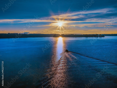 Bass fishermen in a fishing boat on the lake heading into the sunset on a summer afternoon. Beautiful Woods Reservoir located in Southern Tennessee U.S.A.