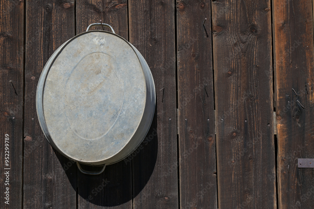 Wooden barn made of old darkened boards with a zinc tub. Texture of old boards as a background.