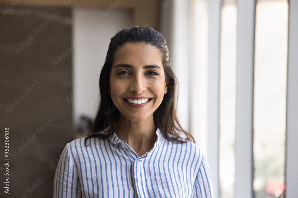 Happy beautiful Hispanic entrepreneur woman in striped casual shirt posing in office, looking at camera with toothy smile. Successful Latin businesswoman professional head shot portrait Happy beautiful Hispanic entrepreneur woman in striped casual shirt posing in office, looking at camera with toothy smile. Successful Latin businesswoman professional head shot portrait