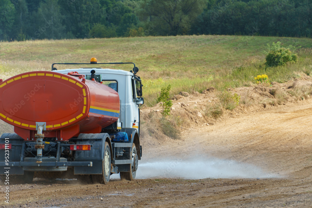 Fototapeta premium A truck pours water on a sandy road to remove dust. Preparation of a dirt track for auto racing. Road works.