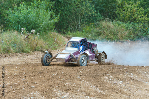 A close-up of an autocross racing car. Clouds of dust and sand burst out from under the wheels. Off-road racing. photo