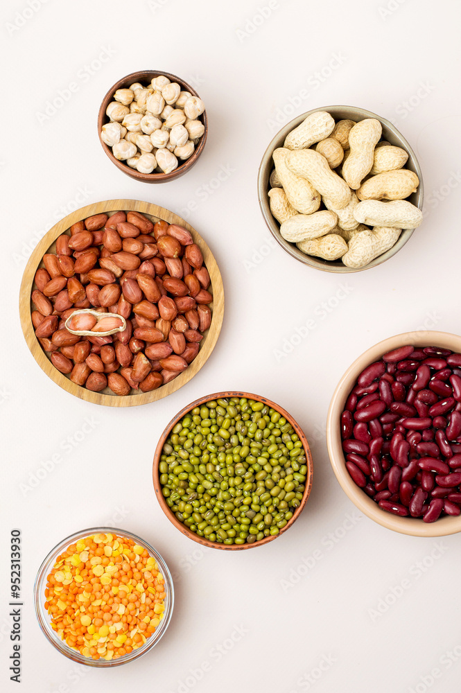 Assortment of legumes in bowls on a light background, top view.  Mung beans, chickpeas, peanuts, beans, lentils.