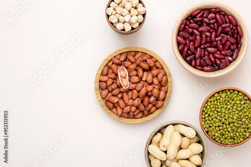 Assortment of legumes in bowls on a light background, top view. Horizontal, free space for text. Mung beans, chickpeas, peanuts, beans, lentils.