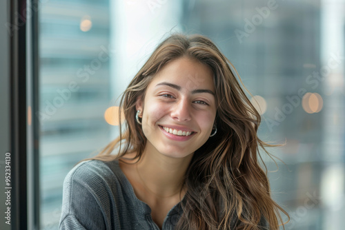 A young attractive professional girl with a hearty smile against soft blurry office window and buildings view background