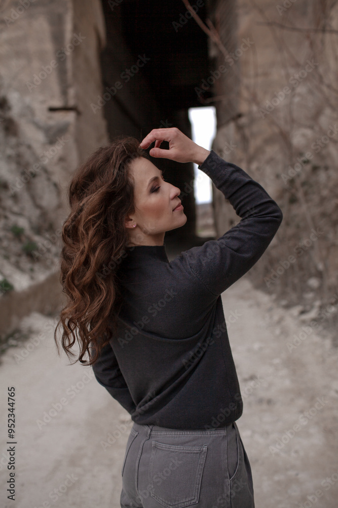 A beautiful woman dressed in gray pants and a sweater walks against the background of a career in stylish clothes A beautiful woman dressed in gray pants and a sweater walks against the background of a career in stylish clothes