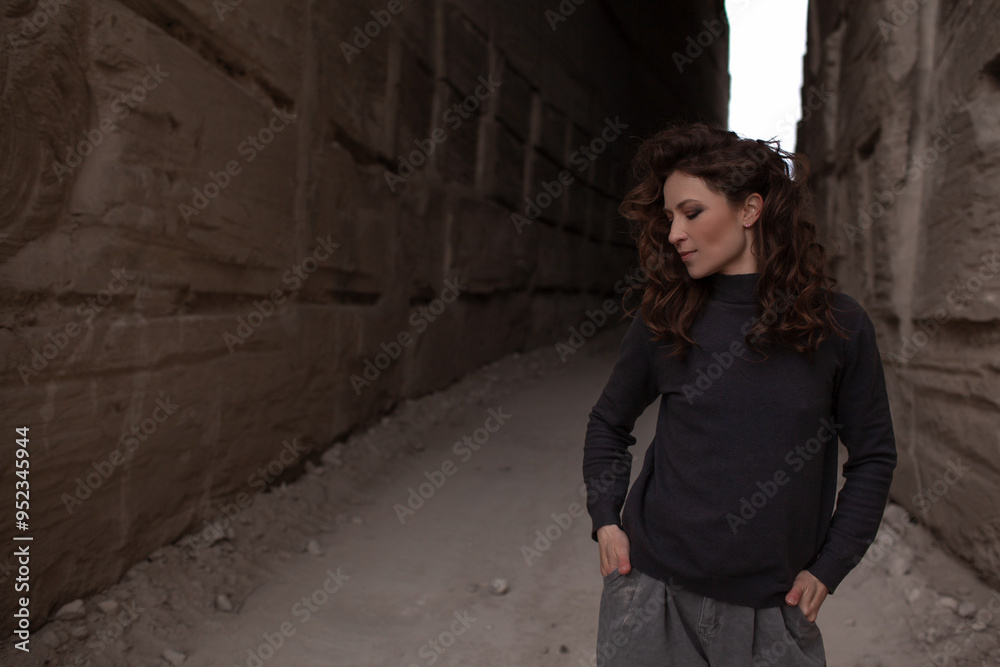 A beautiful woman dressed in gray pants and a sweater walks against the background of a career in stylish clothes A beautiful woman dressed in gray pants and a sweater walks against the background of a career in stylish clothes