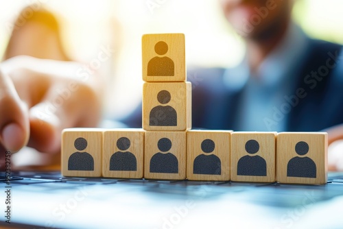 Building a Strong Team:  A close-up shot of wooden blocks representing a team structure, with a blurred businessman in the background.  The image symbolizes leadership, collaboration, and human resour photo