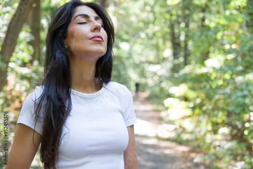 Beautiful woman relaxing and breathing fresh air with sunlight in the summer park