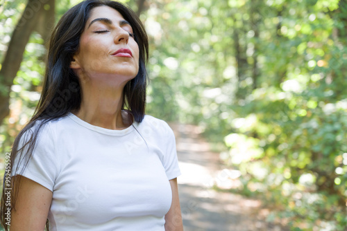 Beautiful woman relaxing and breathing fresh air with sunlight in the summer park