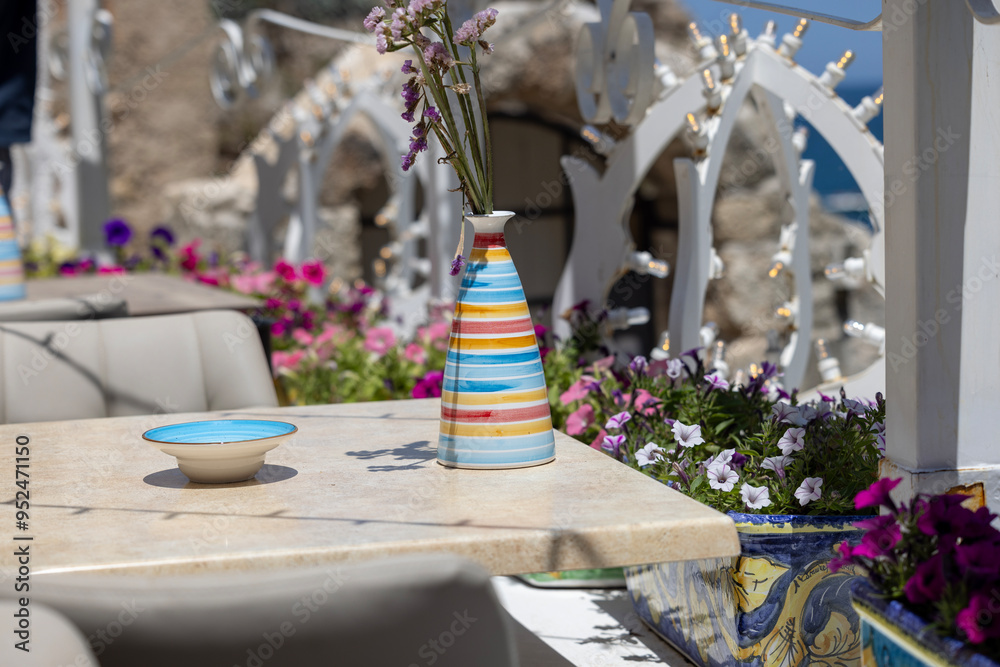 Decorative outdoor restaurant with a ceramic vase with colorful stripes, Italy, Polignano a Mare, Apulia