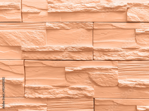 Abstract background of wall lined with decorative stone tiles. Toned Pech color. Close-up. photo