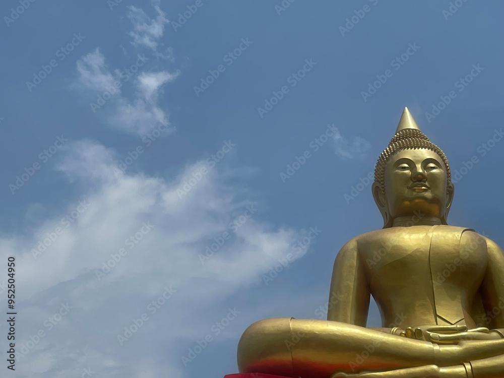A golden Buddha statue with a clear sky in the background, featuring blue and white clouds, creating a peaceful atmosphere. A golden Buddha statue with a clear sky in the background, featuring blue and white clouds, creating a peaceful atmosphere.