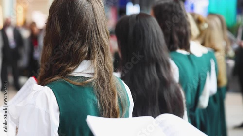 Church choir concert in cathedral, choral artists singing, group of European boys and girls singing in a chorus, students and choristers in white and green uniform performing on stage with conductor photo