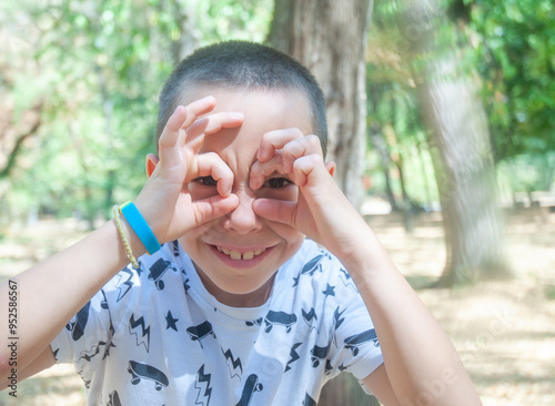 Caucasian boy made binoculars of his hands and holding hands on his face. About 7 years old.
