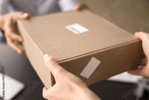 Close up cropped shot of unknown female hands handing over sealed cardboard box to another person, transferring purchased goods to customer, using trusted transportation services. Delivery or dispatch