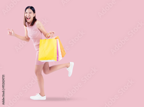 Excited running young woman playfully posing with shopping bags, expressing excitement and fun of successful shopping experience. Image embodies youthful energy and joy of retail therapy.