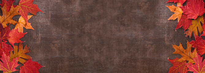 Colorful autumn leaves double border over a dark stone banner background. Above view with copy space.