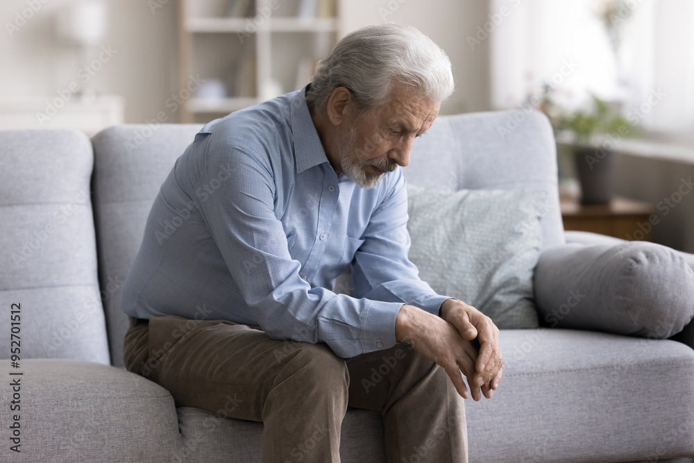 Pensive thoughtful older man sitting alone on couch at home, suffers from solitude, grief or loneliness, looks abandoned, goes through divorce or health problems. Retirement, dementia, senile disease Pensive thoughtful older man sitting alone on couch at home, suffers from solitude, grief or loneliness, looks abandoned, goes through divorce or health problems. Retirement, dementia, senile disease