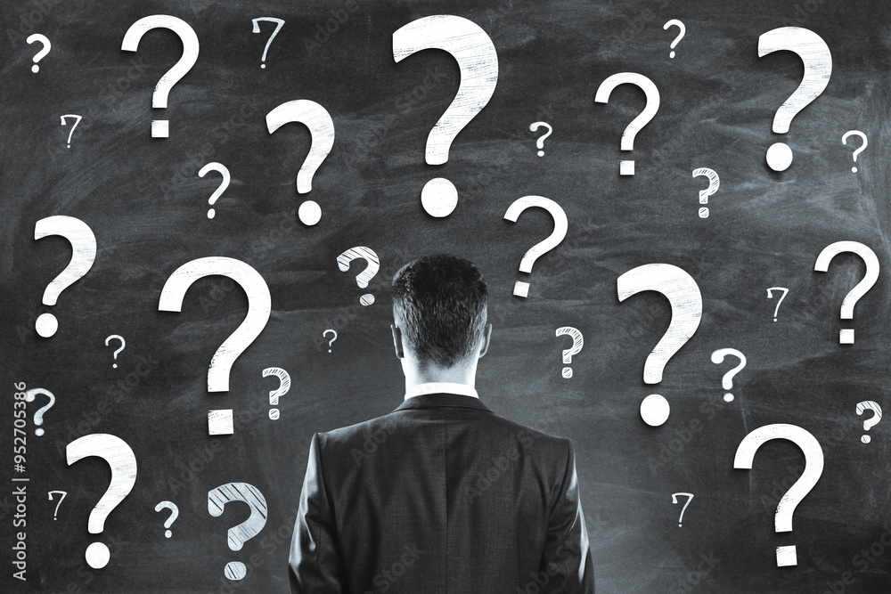 Person in a business suit facing a wall filled with numerous question