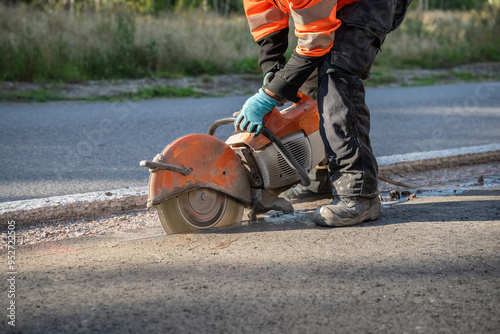 construction worker cuts the asphalt with a circular saw on a road