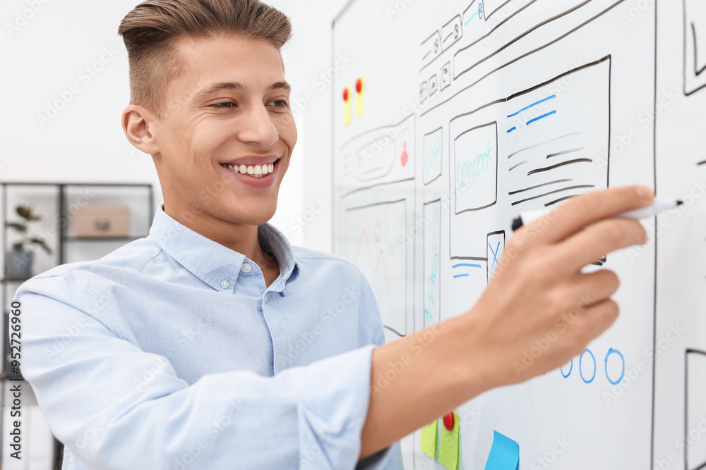 Developing UI design. Man drawing website wireframe on whiteboard indoors Developing UI design. Man drawing website wireframe on whiteboard indoors
