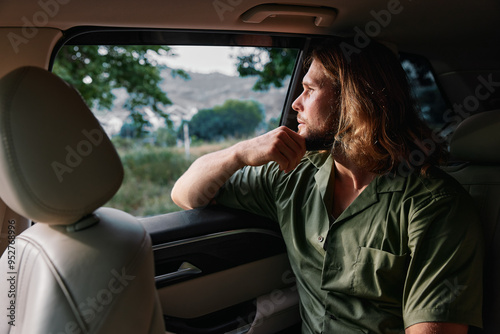 Thoughtful man gazing out of a car window, reflecting on life with a serene landscape in the background