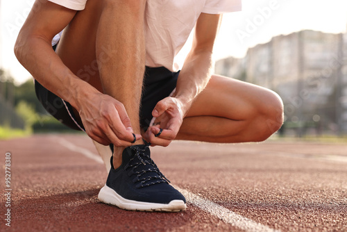 Bilde på lerret Man tying shoelace of black sneaker at stadium, closeup