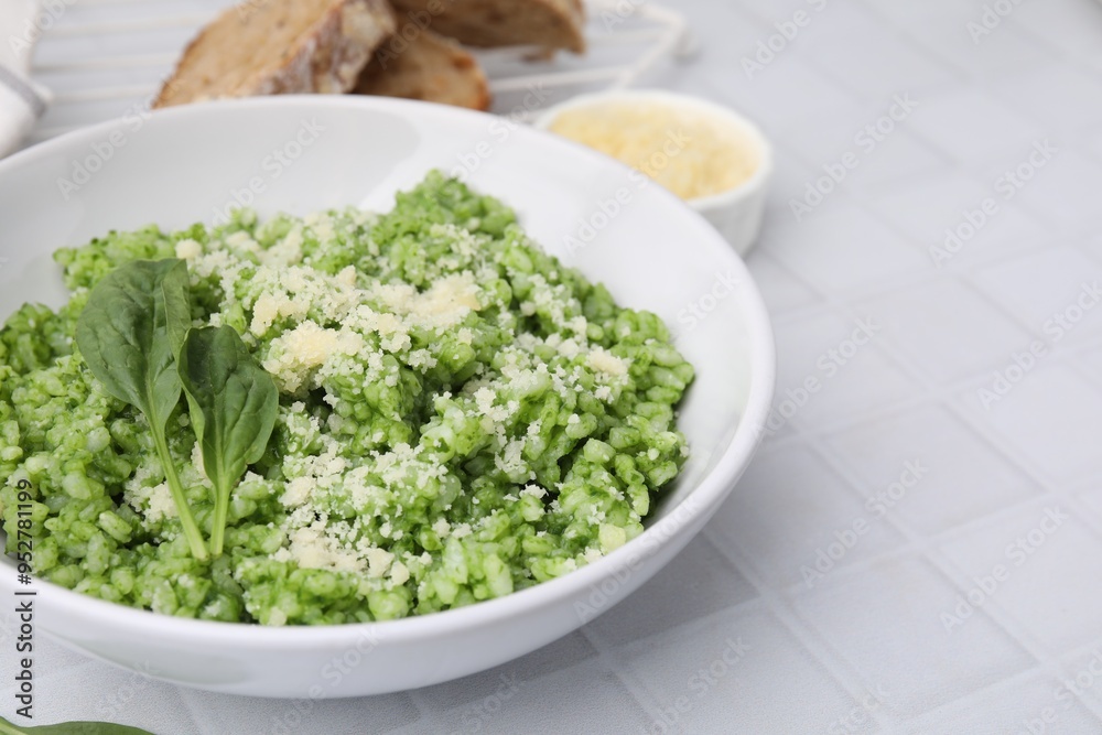 Delicious spinach risotto with parmesan cheese served on white tiled table, closeup. Space for text Delicious spinach risotto with parmesan cheese served on white tiled table, closeup. Space for text