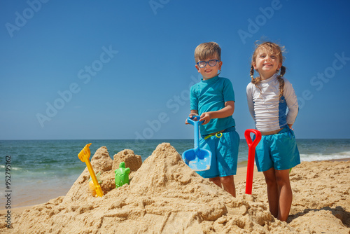 Children building sandcastles, enjoying perfect sunny beach day photo