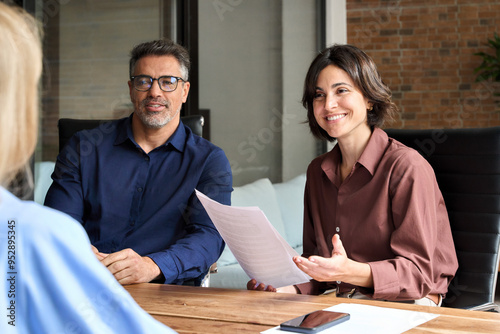 Happy business people team working together in office boardroom. Friendly recruitment hr manager interviewing young woman, holding cv listening to candidate at corporate group meeting or job interview
