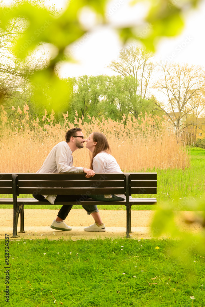 Beautiful loving couple sitting on bench and kissing in park Beautiful loving couple sitting on bench and kissing in park