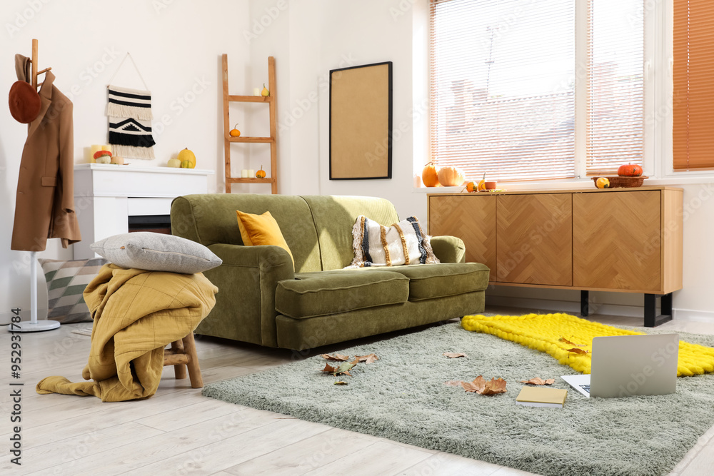 Fototapeta premium Interior of living room with green sofa and fallen leaves