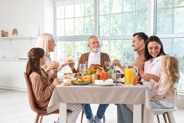 Happy family praying before dinner at festive table on Thanksgiving Day