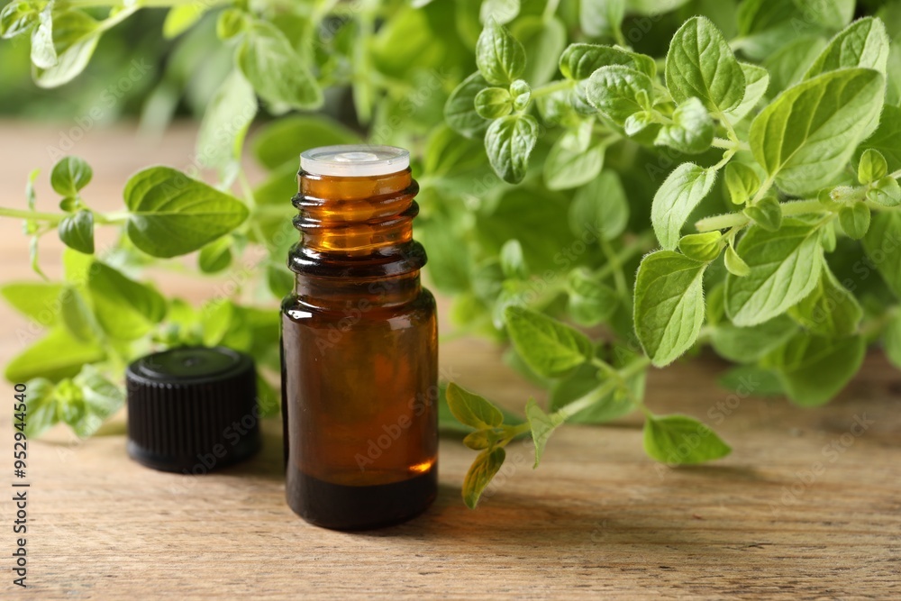 Essential oil in bottle and oregano twigs on wooden table, closeup Essential oil in bottle and oregano twigs on wooden table, closeup