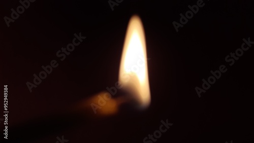 Burning candle in the dark, out of focus.
In complete darkness, a burning candle looks like the photo. The edge of the candle is slightly visible near the flame, and the flickering of the fire appears