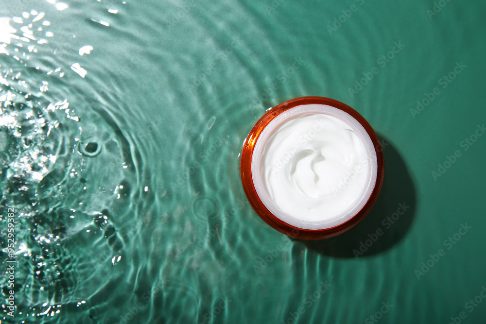 Cosmetic product. Jar with cream in water on green background, top view. Space for text Cosmetic product. Jar with cream in water on green background, top view. Space for text