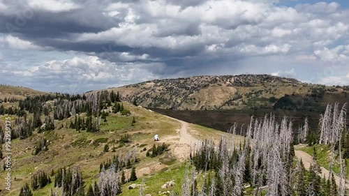Aerial-Mountain ridge-Dark clouds-pulling back-Showing part of the thousands of acres of Engelmann spruce trees killed by bark boring spruce beetles in the Manti-LaSal National Forest in Utah.
