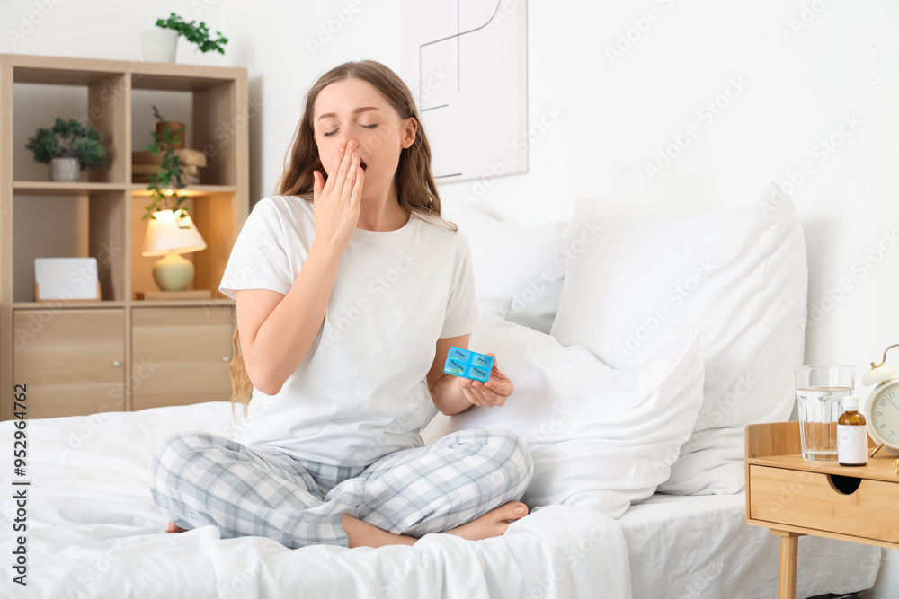 Young woman with box of sleeping pills yawning in bedroom Young woman with box of sleeping pills yawning in bedroom