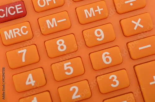 a close-up of an orange calculator, highlighting the numerical keys and basic arithmetic functions commonly used in everyday calculations. photo