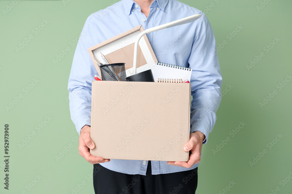 Fired young man holding box with personal stuff on green background, closeup Fired young man holding box with personal stuff on green background, closeup