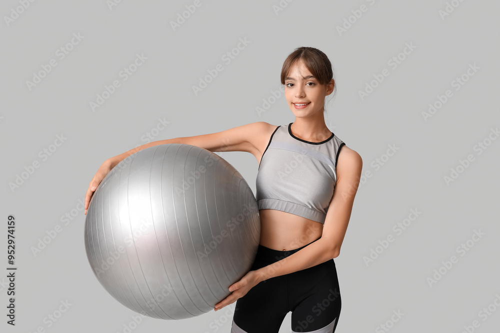 Young woman with fitball on grey background Young woman with fitball on grey background